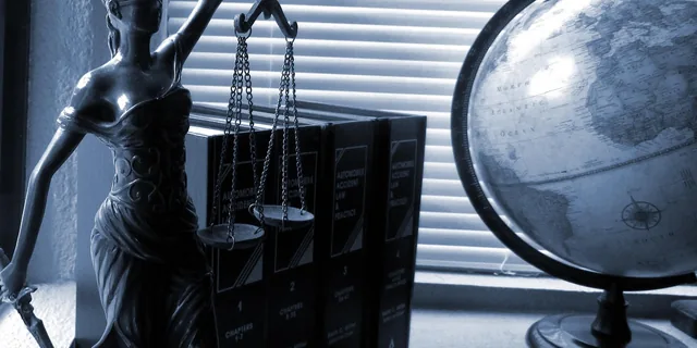 Statue af Justitia med vægt ved siden af en globus og bøger